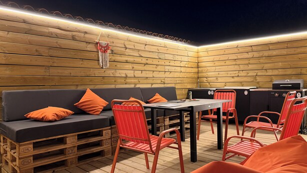 A wooden deck with a sofa, chairs, a table, and a grill. - La'PaillotteduBassin Vacation Rental (Le Teich)