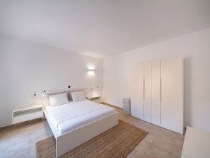 A bedroom with a bed, bedside tables, a wardrobe, and a wall-mounted light fixture. - CASA 3 Lindos (Lindos)