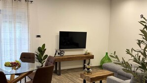 Un salon moderne avec un téléviseur, des sièges, une table à manger et des plantes.