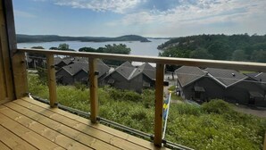 A wooden deck with a view of a lake, surrounded by houses with sloped roofs. - 5 Star Holiday Home in Uddevalla (Uddevalla)