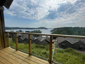 Une terrasse en bois offrant une vue sur un lac, entourée de maisons aux toits inclinés.