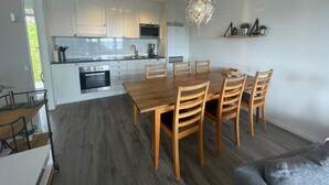 A modern kitchen with white cabinets, a dining table with wooden chairs, and a chandelier. - 5 Star Holiday Home in Uddevalla (Uddevalla)