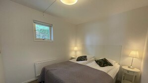 Un dormitorio con una cama, dos lámparas de noche, un ventanal y un radiador.
