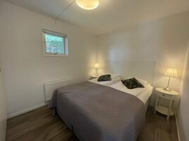 Un dormitorio con una cama, dos lámparas de noche, un ventanal y un radiador.