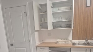 A compact kitchen with white cabinets, a dishwasher, and a wooden countertop. - Home  away from home, clean,  cozy and comfortable (Saskatoon)