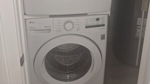 A stacked washer and dryer unit with control panels and a door. - Home  away from home, clean,  cozy and comfortable (Saskatoon)