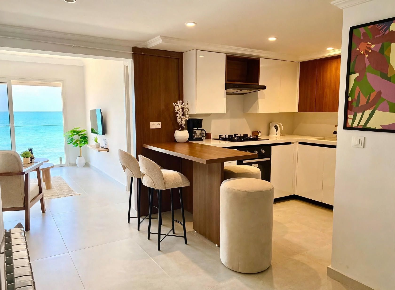 A modern kitchen with a bar area, a dining set, and a view of the sea.