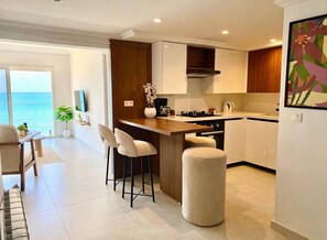 Una cocina moderna con barra, un comedor y vistas al mar.