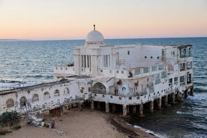 Un edificio grande, blanco y de varios pisos con una cúpula, ubicado junto al mar.