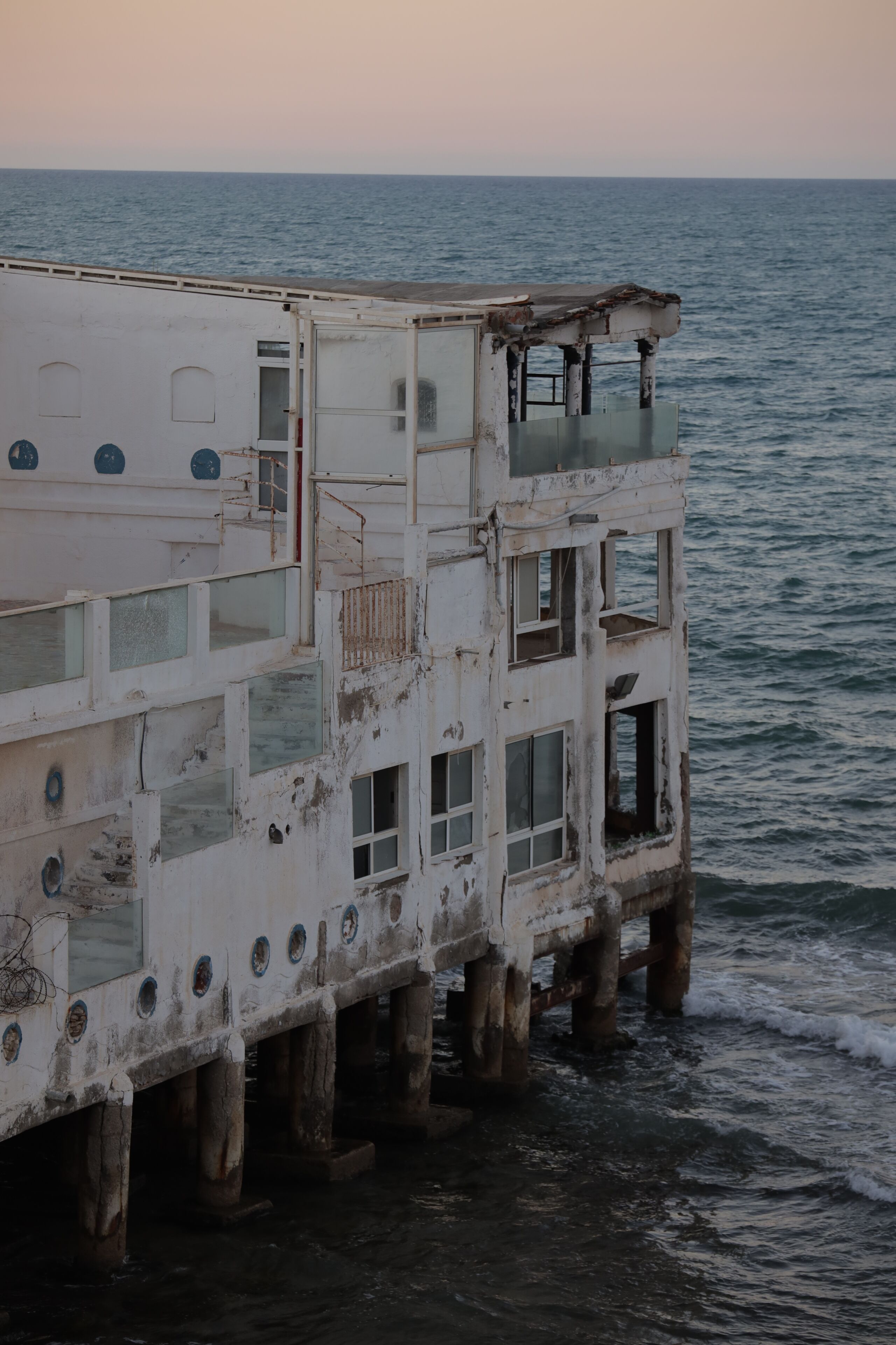 A multi-level building with balconies, windows, and a view of the sea.