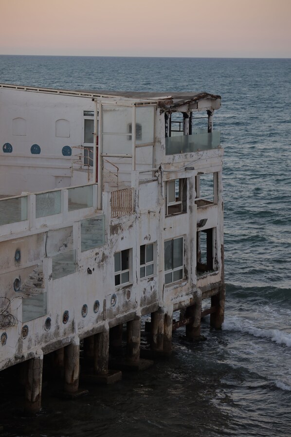 Un edificio de varios niveles con balcones, ventanas y vista al mar.