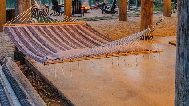Une terrasse en bois avec des hamacs, des sièges d’extérieur et des guirlandes lumineuses.