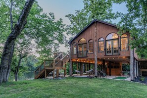 Eine Holzhütte mit einer Terrasse, großen Fenstern und einer Treppe zu einem Balkon.