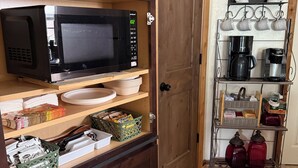 Una cucina con un forno a microonde, scaffali con stoviglie e una macchina per il caffè.