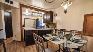 Una cucina con tavolo da pranzo per quattro persone, pensili in legno e una lampada a sospensione.
