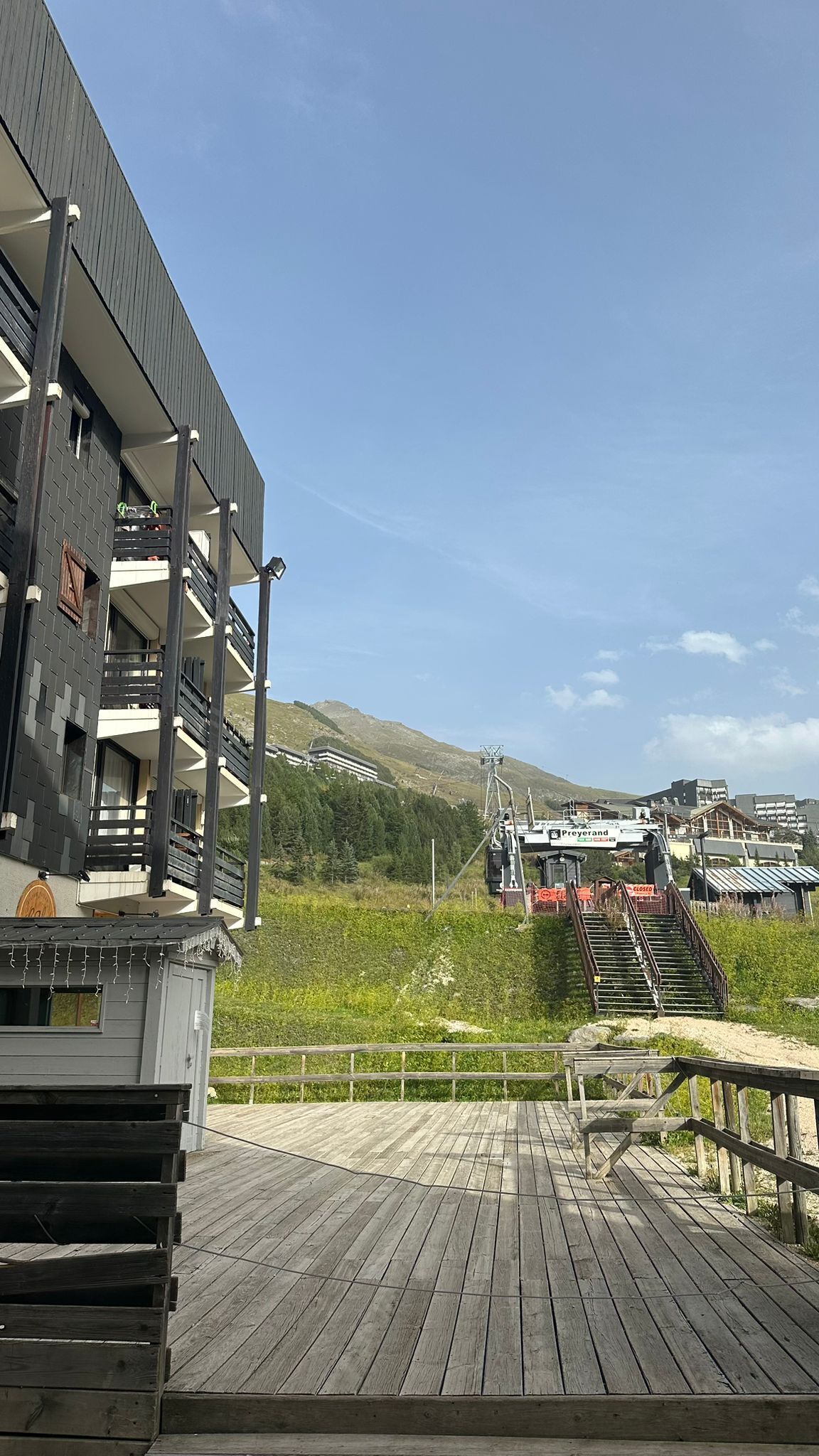 A wooden deck with a view of a mountain and a building with balconies.