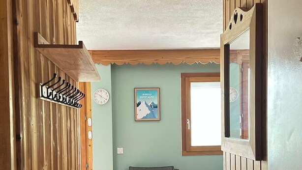Een houten interieur met een bank, een tafel en een wandklok.