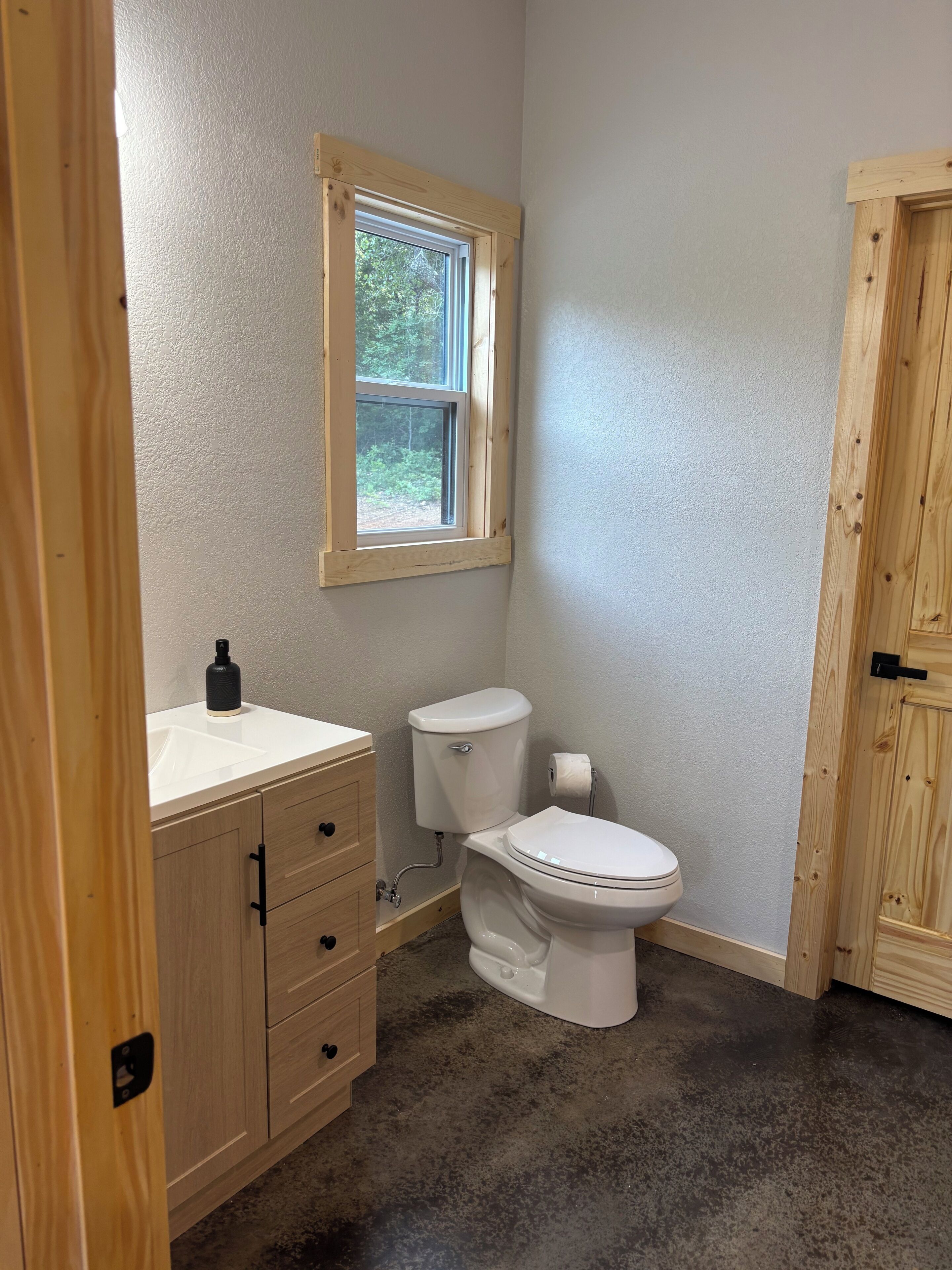 A bathroom with a toilet, sink, and wooden cabinets.