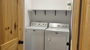 Lavandería con dos lavadoras y una secadora, puertas de madera y una lámpara en el techo.
