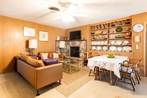 A living room with a sofa, fireplace, dining table, and shelves with decorative items. - 3-bedroom, 2-bath house in beautiful downtown Bastrop.  Great yard and scenery. (Bastrop)
