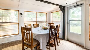 Un comedor con una mesa dispuesta para seis personas, sillas de madera y un ventilador de techo.