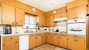 Una cocina con armarios de madera, lavavajillas, microondas y refrigerador.