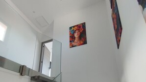 Uma escada moderna com guarda-corpos de vidro, um quadro na parede e uma porta que dá para outro cômodo.
