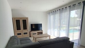 Uma sala de estar moderna com um sofá seccional, uma TV de tela plana, um armário de madeira e uma mesa de centro.