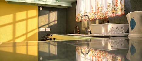 Una cocina con estufa, fregadero y ventana con cortina estampada.
