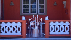 Ein rotes Gebäude mit einem weißen Tor, einem Fenster mit dekorativem Rahmen und zwei Wandleuchten.