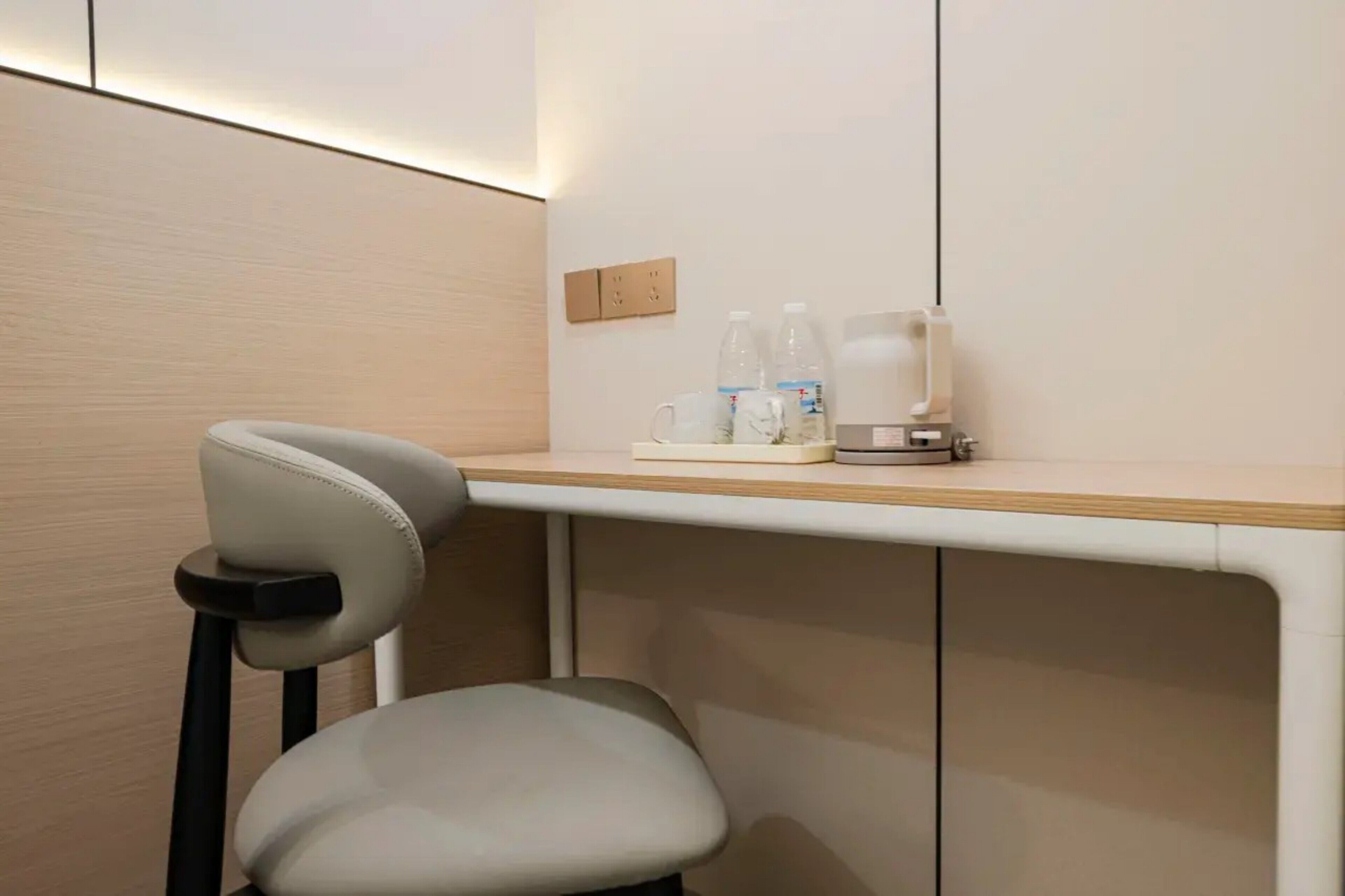 A modern room with a white chair, a wooden desk, and a water dispenser.