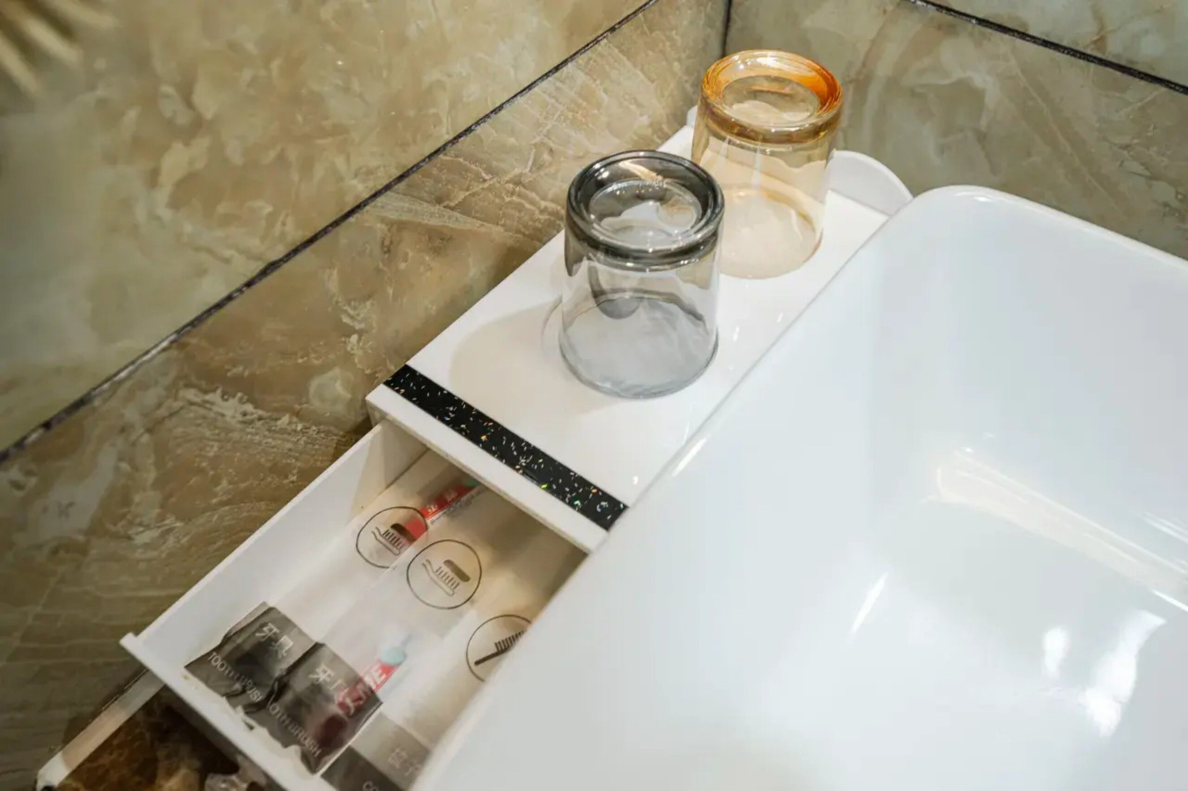 A bathroom with a white sink, a glass jar, and toiletries on the counter.