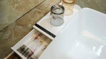 A bathroom with a white sink, a glass jar, and toiletries on the counter.
