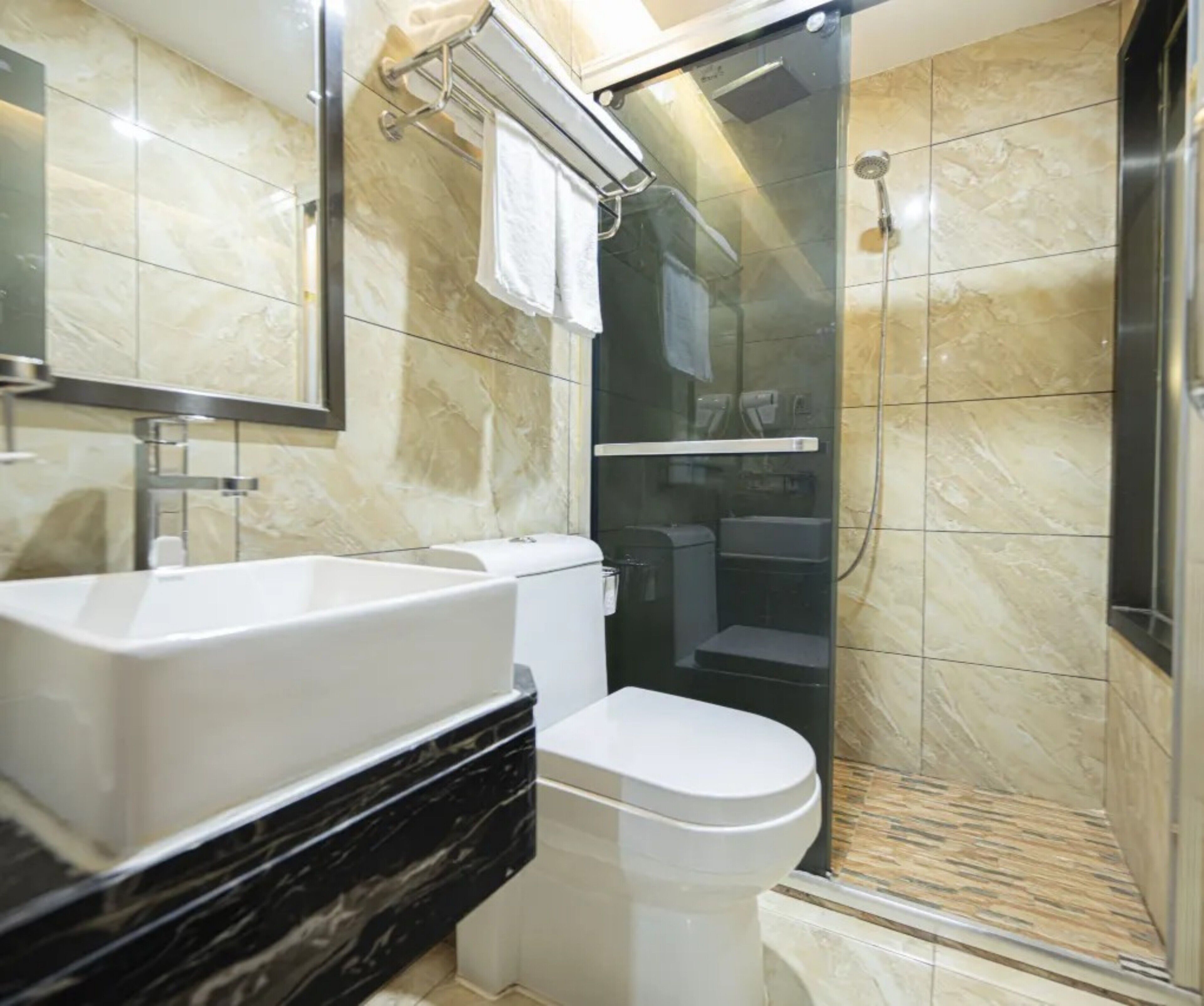 A modern bathroom with a large sink, toilet, and glass-enclosed shower.