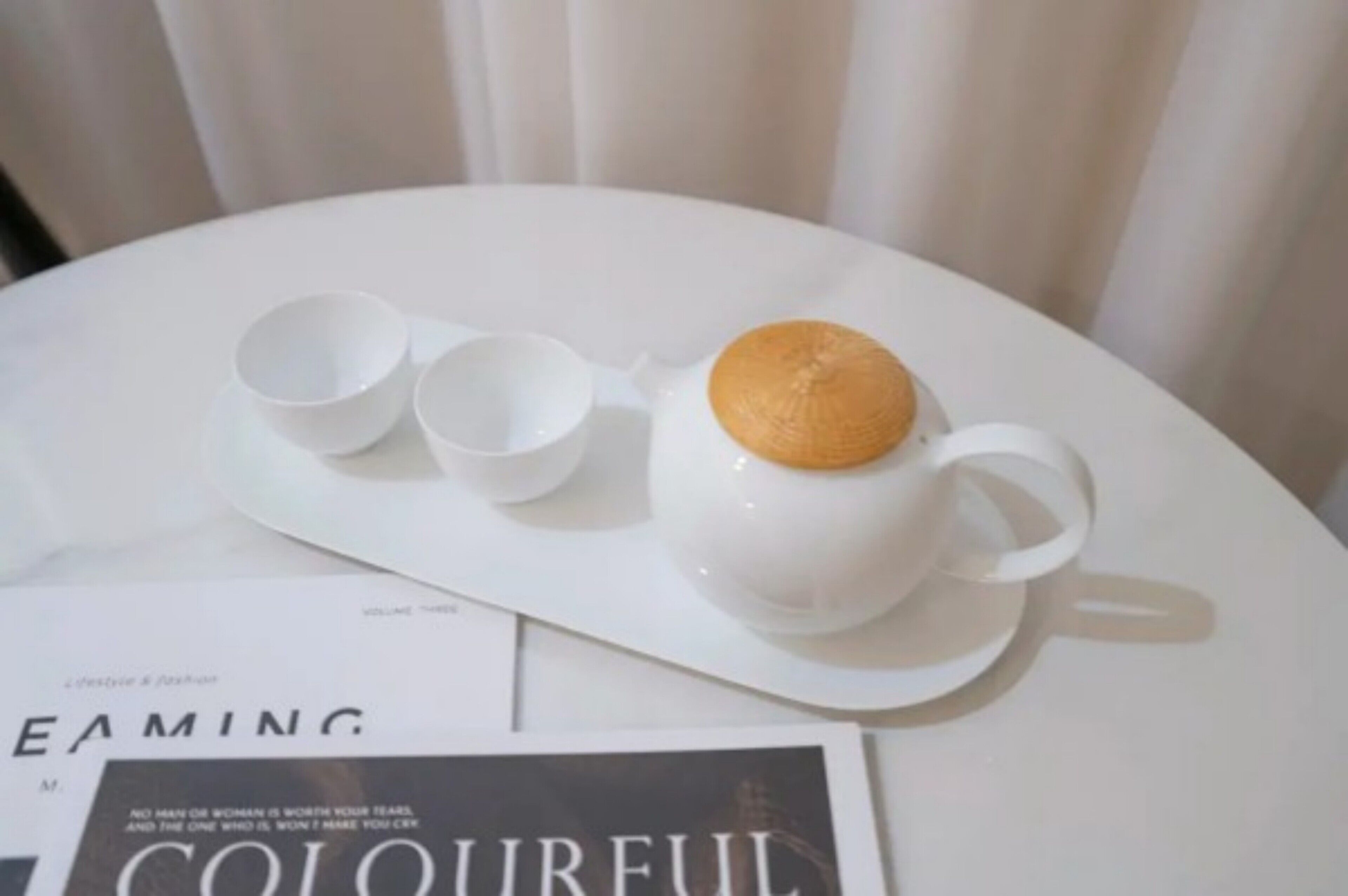 Una mesa blanca con una taza blanca y dos tazas más sobre una bandeja blanca.