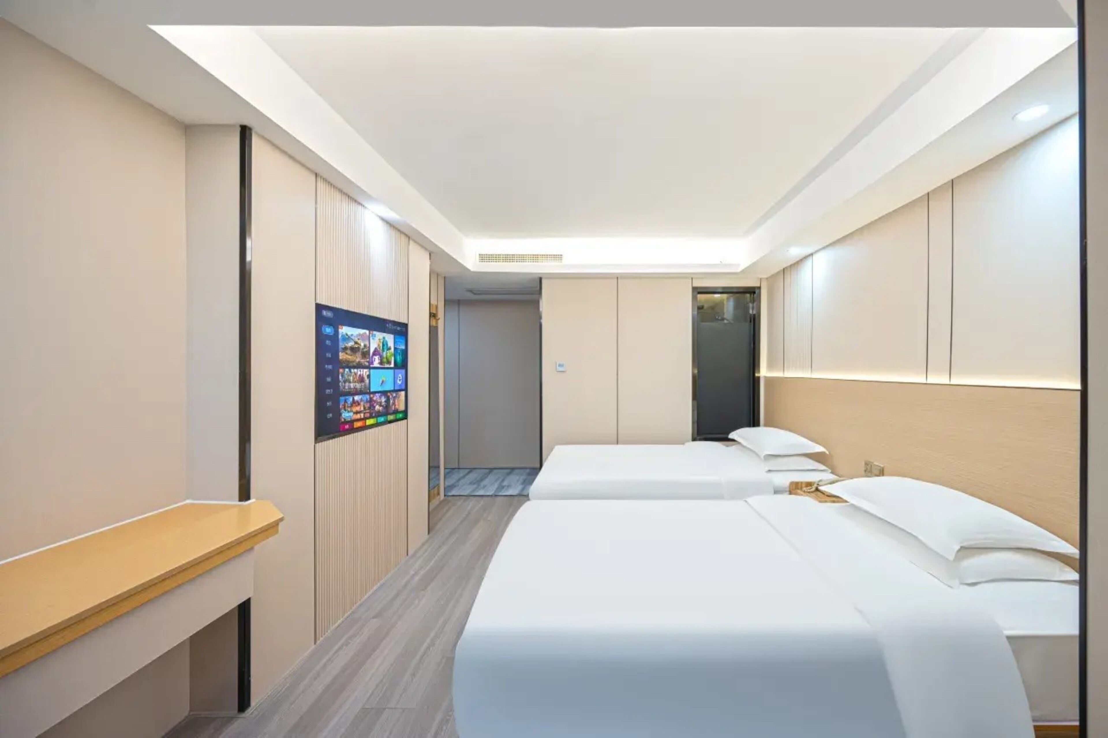 A hotel room with two beds, a desk, a TV, and a wardrobe.