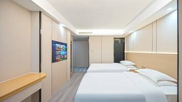 A hotel room with two beds, a desk, a TV, and a wardrobe.