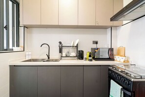 A kitchen with a sink, microwave, stove, and cabinets. - Modern 1BR Near JKIA & SGR | Pool, Gym & Free Parking (Nairobi)