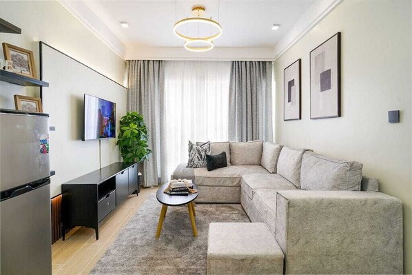 Una sala de estar moderna con un sofá, una mesa de centro, un televisor y un refrigerador.