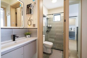 Un baño moderno con cabina de ducha de vidrio, un lavabo blanco y un espejo.