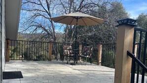 A patio with a table and chairs, an umbrella, and a view of trees. - Peaceful Gold Country Studio Near Yosemite & Black Oak Casino (Tuolumne)