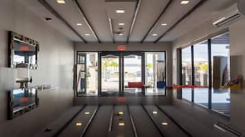 Eine moderne Hotelhalle mit einem spiegelnden Boden, einem Empfangstresen und Blick ins Freie.