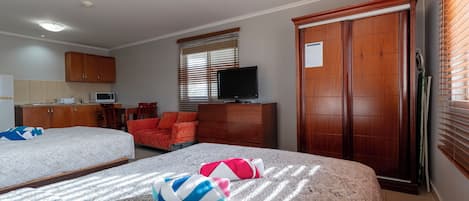 Habitación de hotel con dos camas, televisión, escritorio con ordenador y armario.