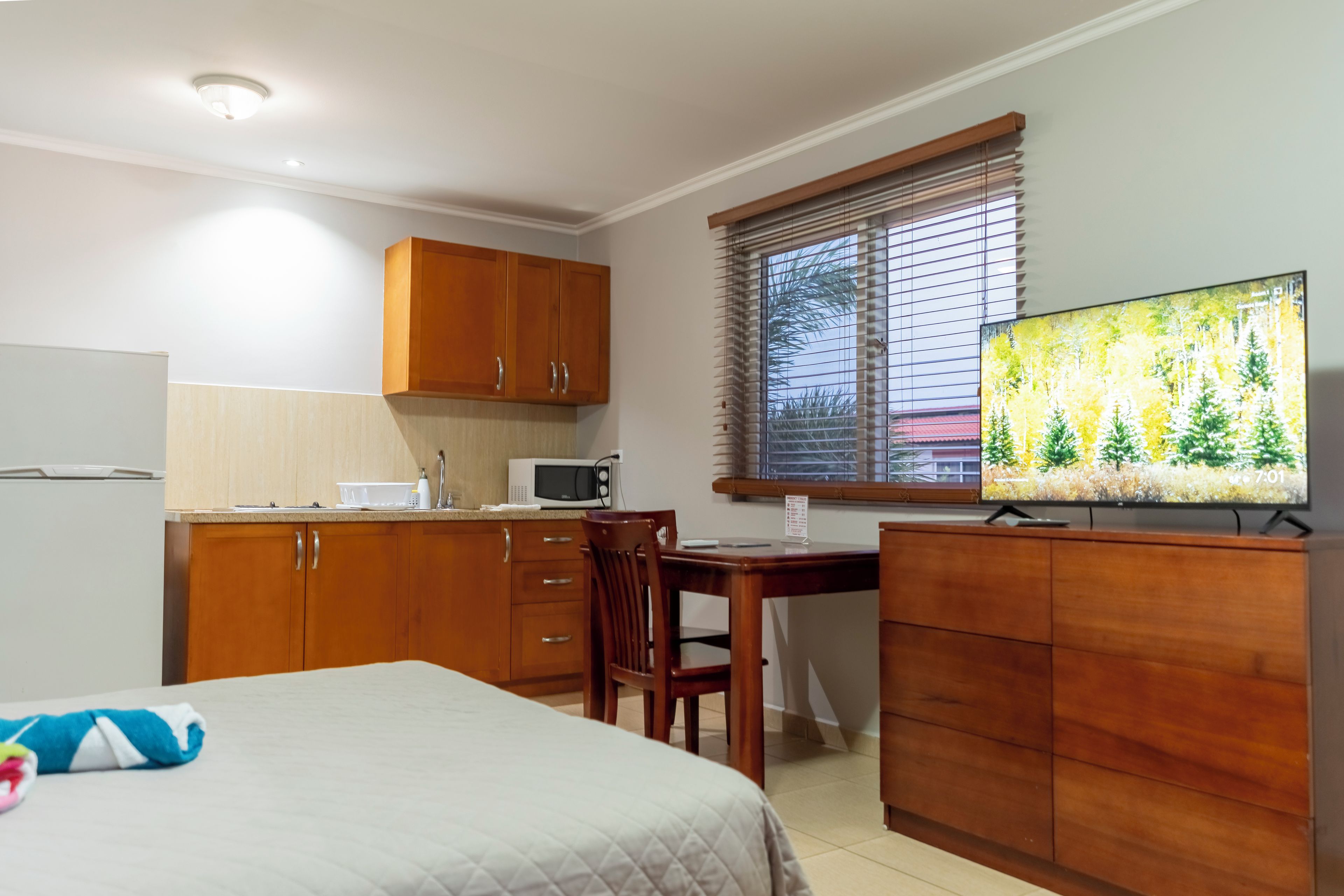 A compact kitchen with wooden cabinets, a microwave, and a dining area with a table and chairs.
