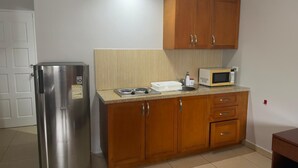 A compact kitchen with a stainless steel refrigerator, wooden cabinets, a microwave, and a sink. - Dorado Eagle Beach Hotel (Eagle Beach)