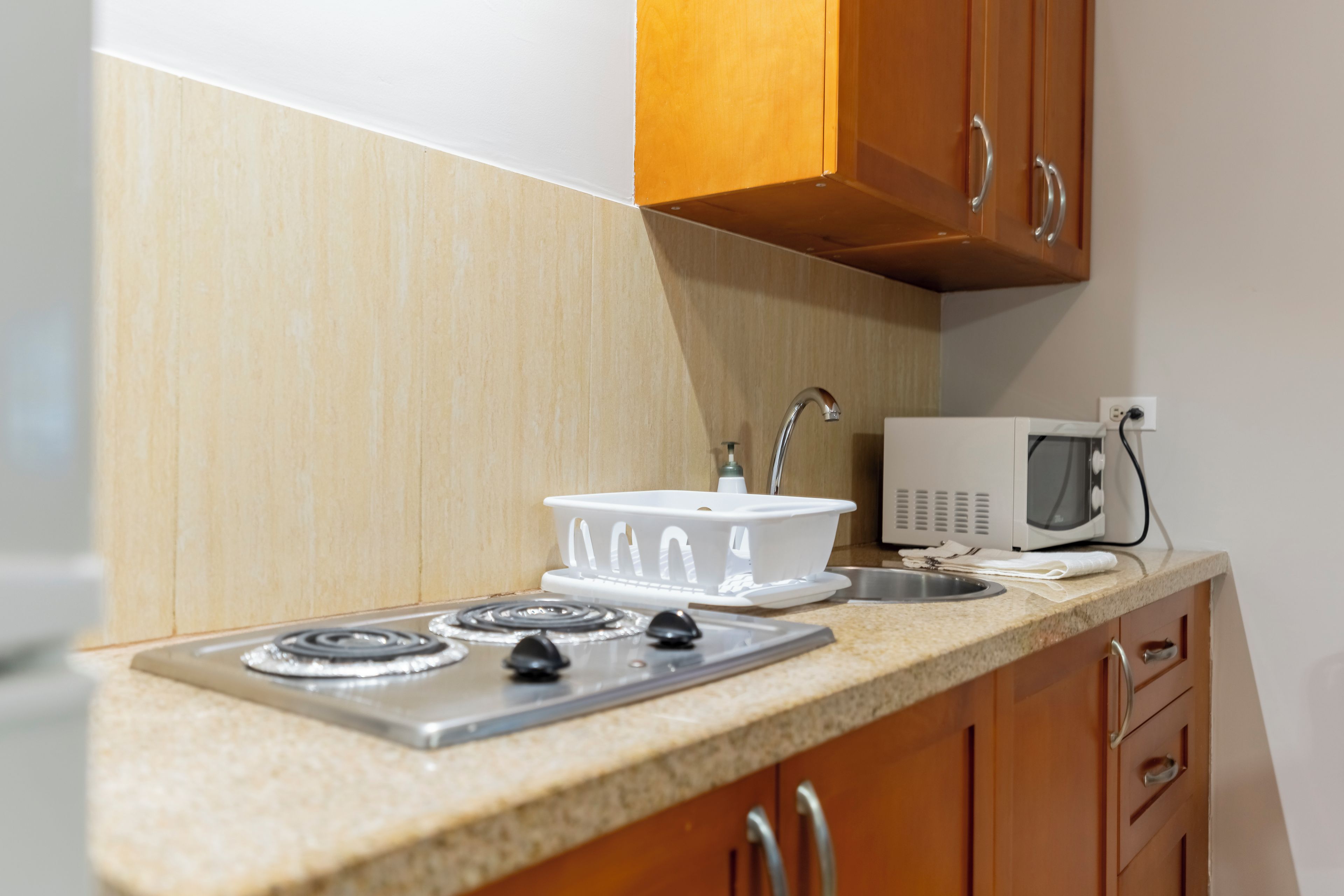 Una cocina con estufa, microondas y pileta.