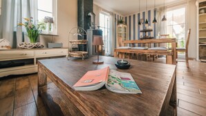 Une table de salle à manger en bois, avec des livres, une bougie et un vase rempli de fleurs.