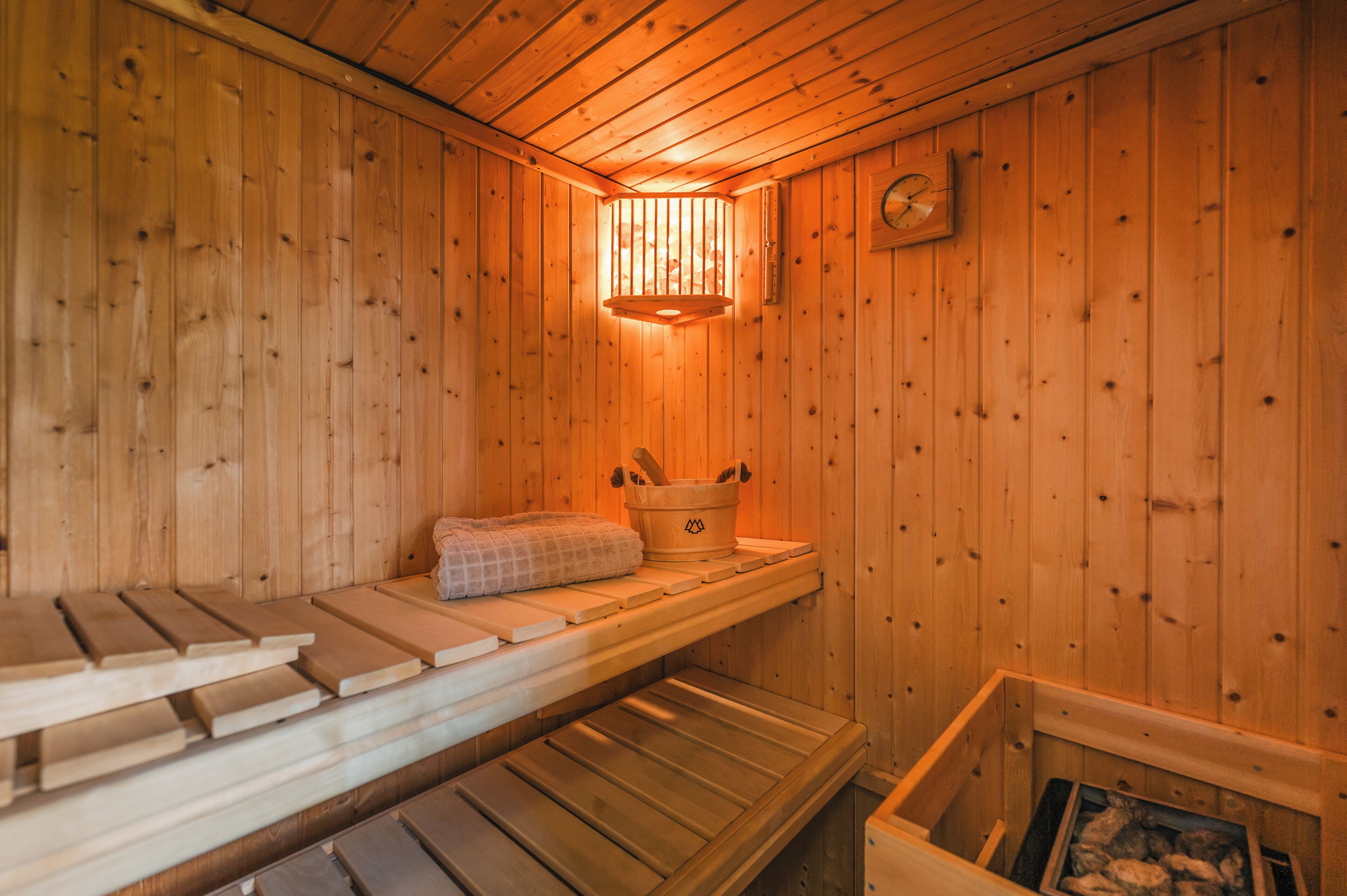 Eine Holzsauna mit Bänken, einem Handtuch und einem Eimer.