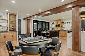 Eine moderne Küche mit Holzbalken, einem Essbereich mit rundem Tisch und Blick durch eine Glastür.