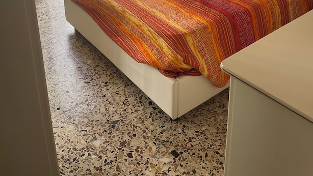 Ein Schlafzimmer mit einem Bett, einem Nachttisch, einer Vase und einer Deckenleuchte.